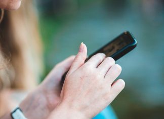Savremeni trendovi online zabave: Zašto sve više korisnika bira 1xBet Devojka drži mobilni telefon u ruci