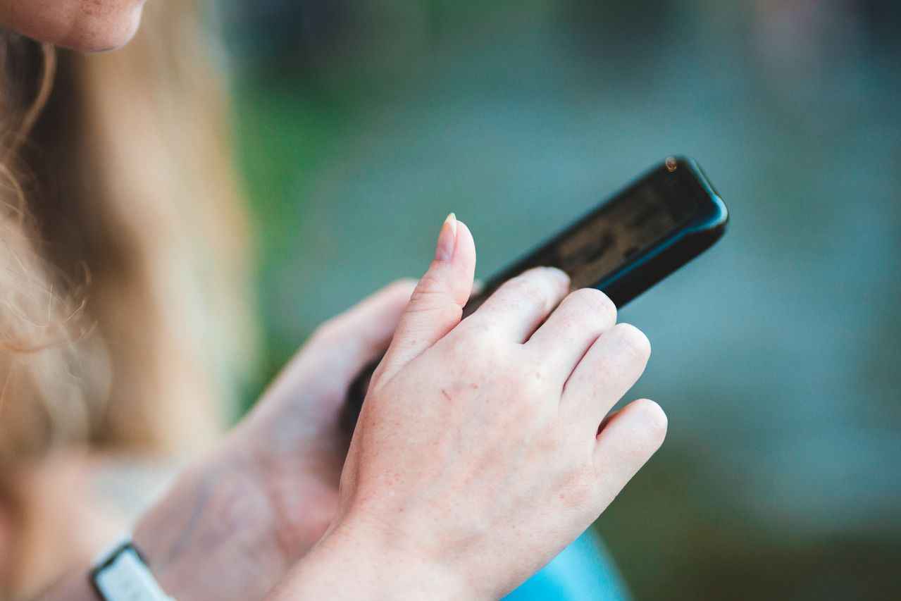 devojka-mobilni-telefon Devojka drži mobilni telefon u ruci