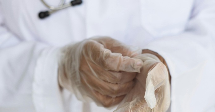 Doktor stavlja rukavice na ruke.