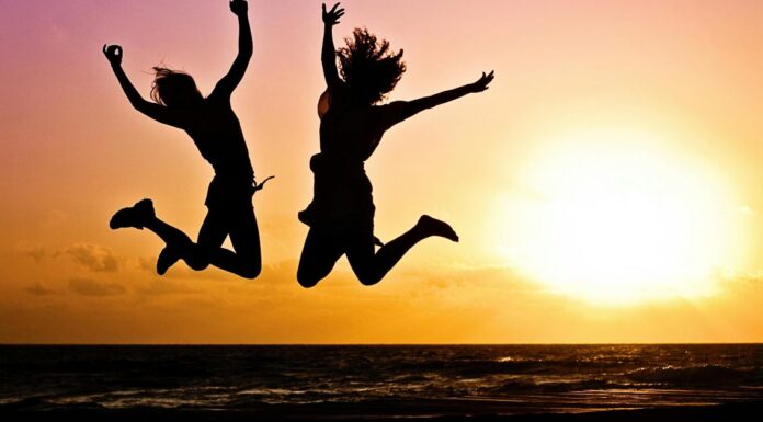 Dvoje ljudi skaču, zalazak sunca u pozadini