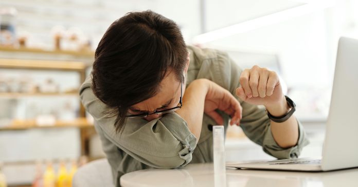 Čovek kija dok sedi za stolom