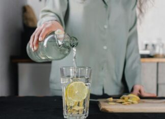 Ishrana i detoksikacija: Kako telo oporaviti od slavske hrane? Osoba sipa vodu u staklenu čašu u kuhinji.