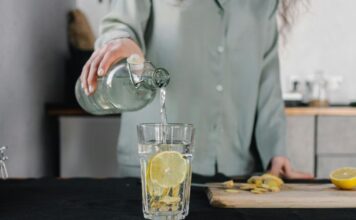 Ishrana i detoksikacija: Kako telo oporaviti od slavske hrane? Osoba sipa vodu u staklenu čašu u kuhinji.