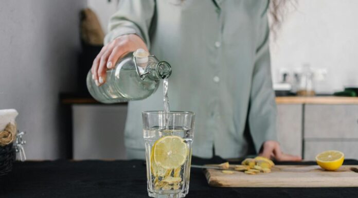 Ishrana i detoksikacija: Kako telo oporaviti od slavske hrane? Osoba sipa vodu u staklenu čašu u kuhinji.