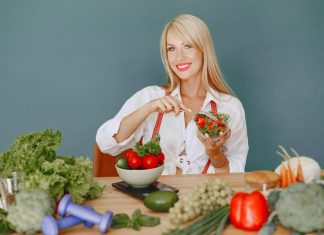 Plavokosa žena drži činiju salate u kuhinji