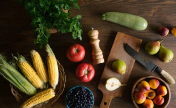 Ishrana koja čuva zdravlje debelog creva,i kada je vreme za pregled Raznovrsno povrće na dasci i drvenom stolu.