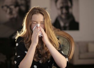 Devojka sedi u fotelji i kija