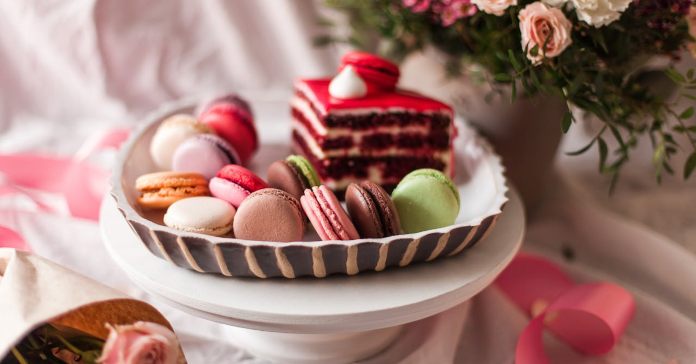 Činija sa makaronsima i tortom oko koje se nalazi cveće.