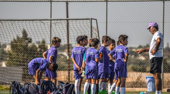 Kako profesionalni trening utiče na telo mladih sportista? Trener razgovara sa decom u ljubičastim dresovima na fudbalskom terenu