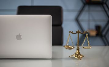 Uticaj pravne sigurnosti na smanjenje stresa kod preduzetnika i rekreativaca Na stolu se nalaze laptop i figura vage.