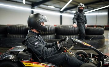 Vozač u kartingu sa crnom kacigom sedi u gokartu spreman za vožnju