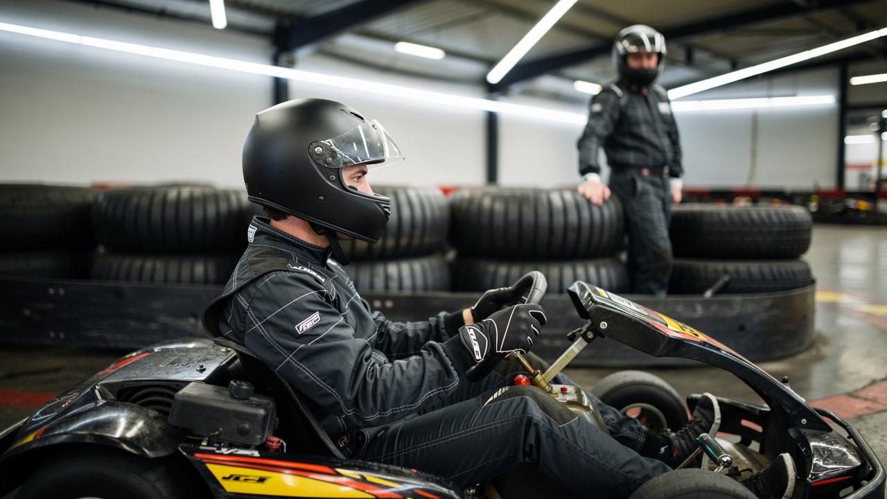 vozac-karting-kaciga Vozač u kartingu sa crnom kacigom sedi u gokartu spreman za vožnju