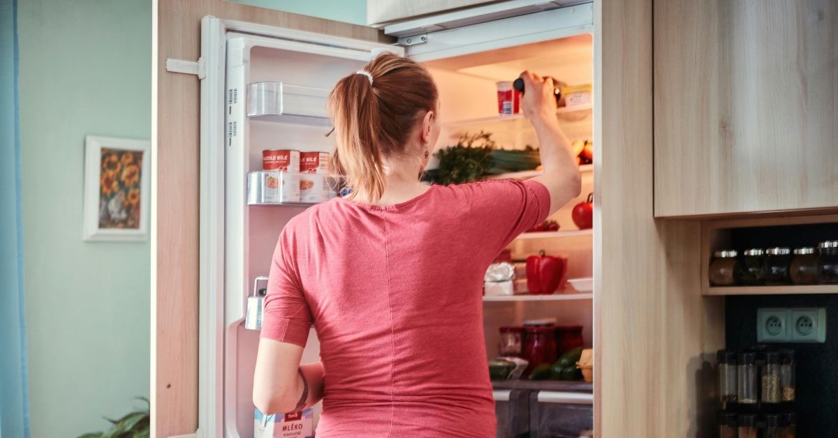 zena-frizider Žena uzima nešto iz frižidera