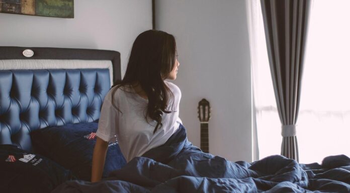 Zašto se mišići sporije oporavljaju ako ne spavate dovoljno? Žena sedi na krevetu i gleda kroz prozor