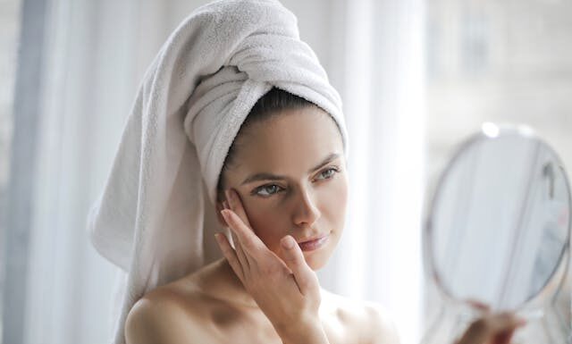 Žena sa peškirom se gleda u ogledalo