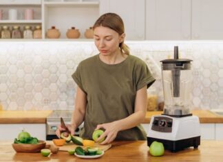 Žena seče voće i povrće u kuhinji pored sokovnika