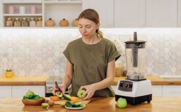 Savremeni izazovi u planiranju uravnotežene ishrane! Žena seče voće i povrće u kuhinji pored sokovnika