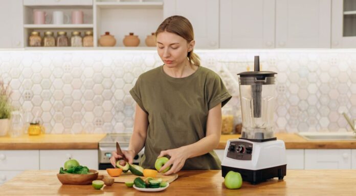 Žena seče voće i povrće u kuhinji pored sokovnika